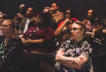 Seated crowd looks toward stage.