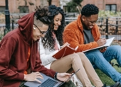Photo of three BIPOC students studying and smiling