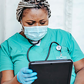 doctor in green scrubs reading a tablet