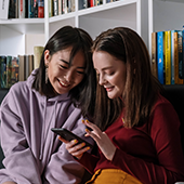 teen girls looking down at a cell phone