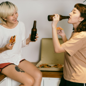 two women drinking and eating pizza