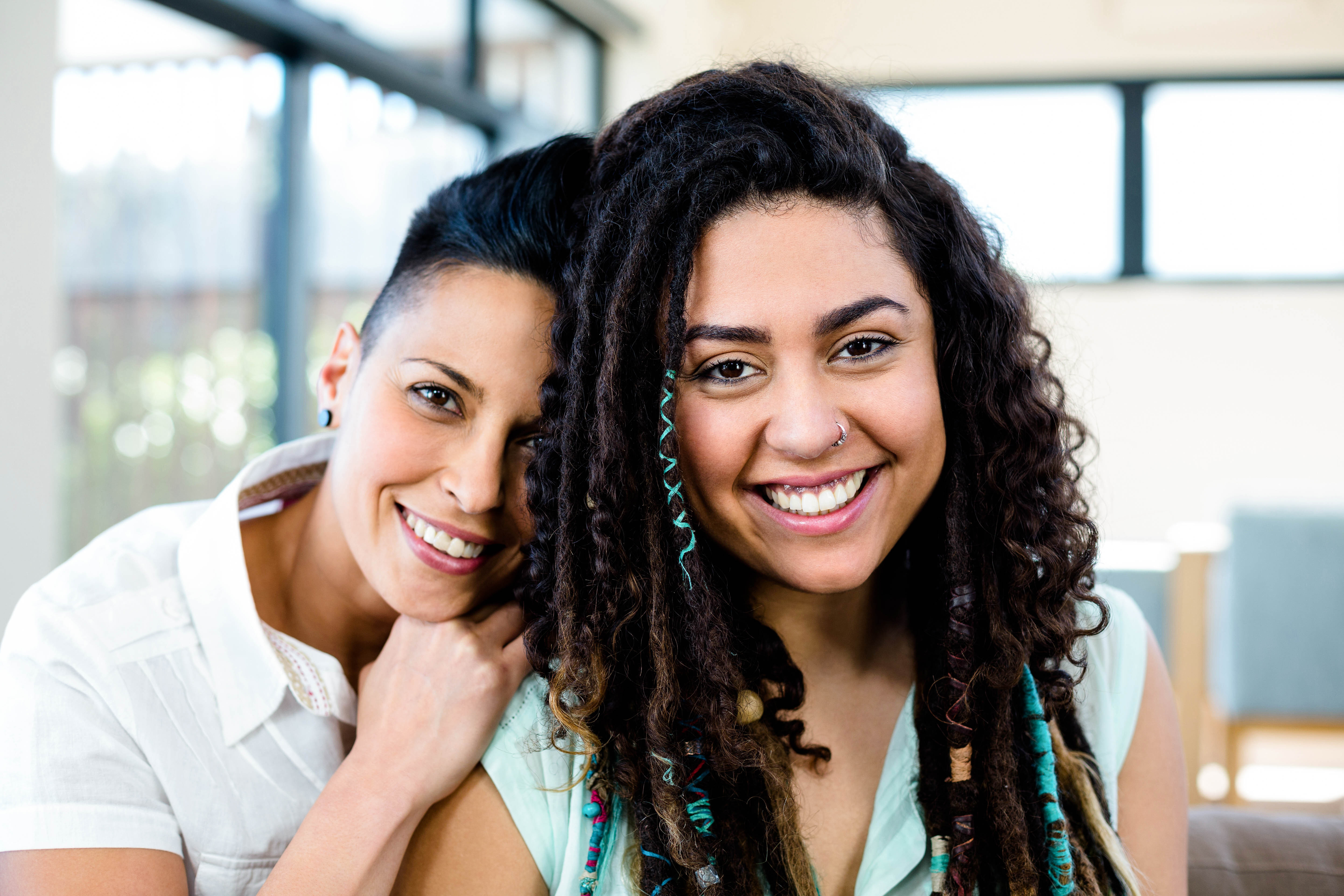 two AFAB people, smiling and embracing