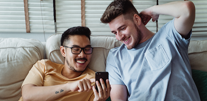 Two men smiling and looking at a cell phone.