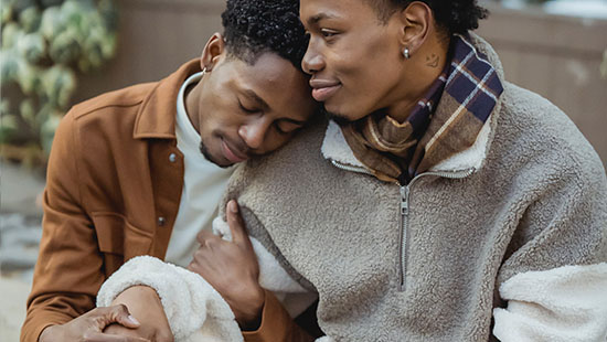 Two Black men hugging.